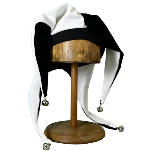 Black and white jester hat with silver bells, front view on wooden stand