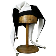 Black and white jester hat with silver bells, front view on wooden stand
